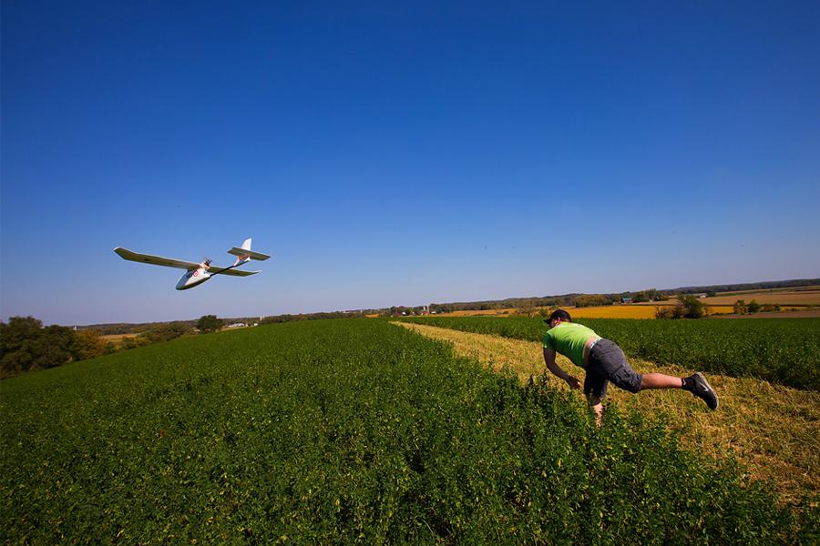 一名学生将一架测绘无人机扔到田野里.
