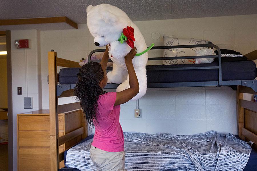 学生在宿舍里举起大泰迪熊.