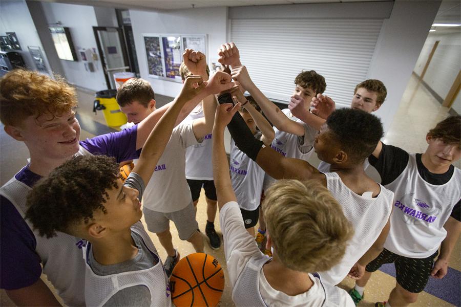 参加篮球夏令营的男孩们把手放在一起.