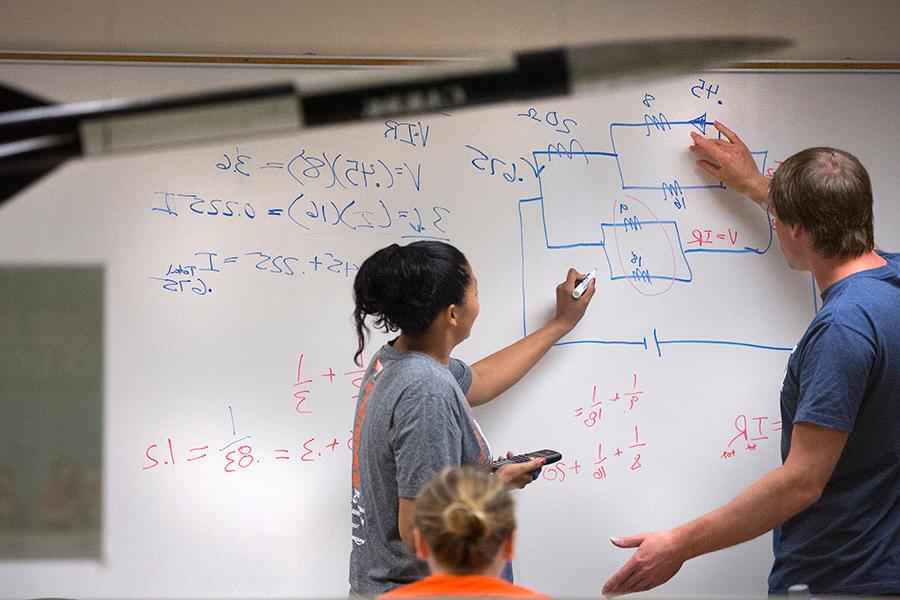 Physics students taking a test on a whiteboard